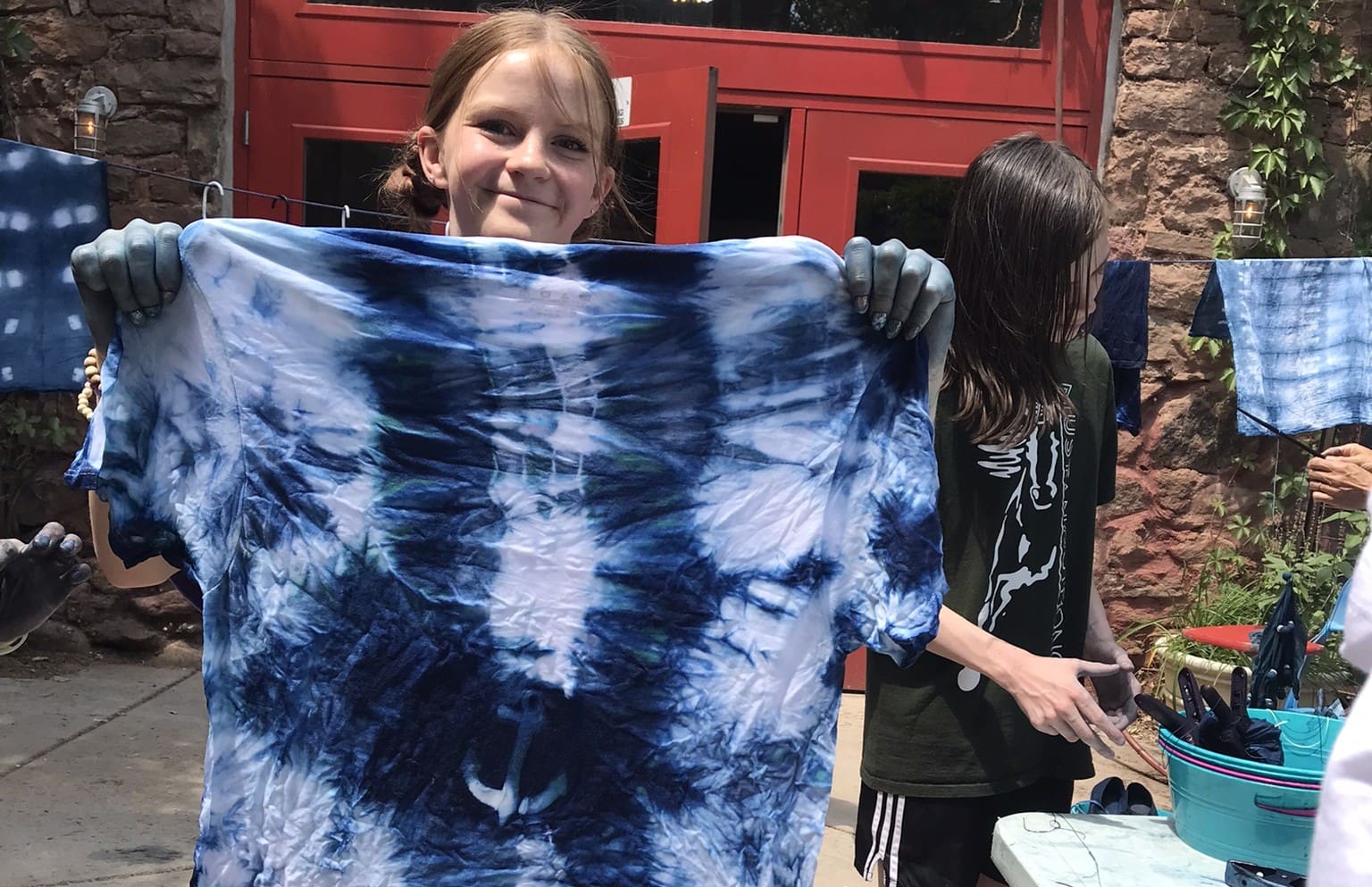 A young girl holds up fabric dyed with indigo blue dye
