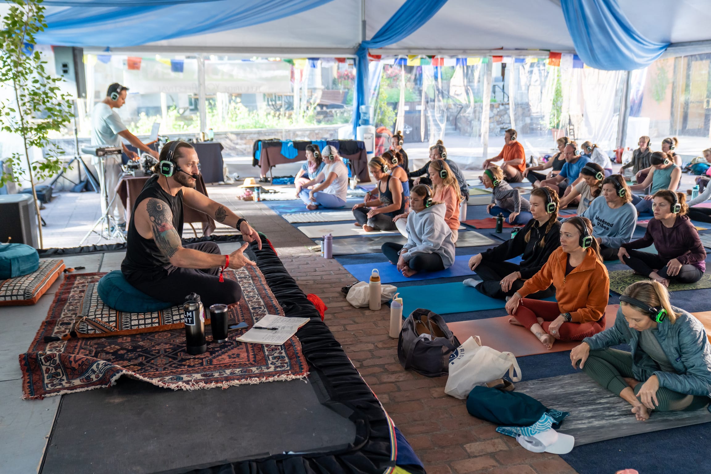 A group of people wearing headphones participate in a yoga session together.