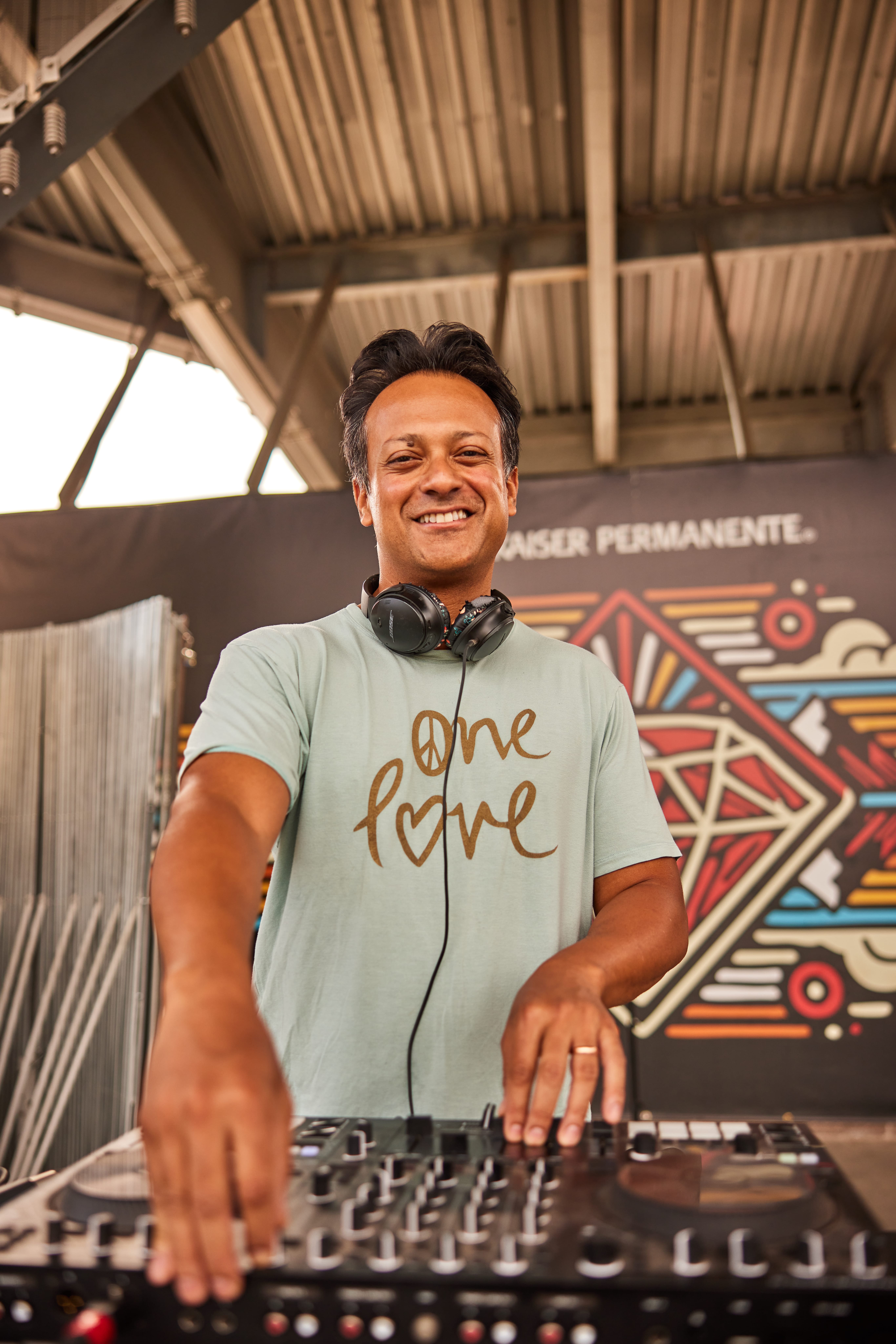 A man stands smiling at a DJ sound board.